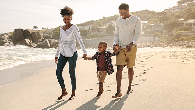 Paar, das mit seinem Kind am Strand spazieren geht