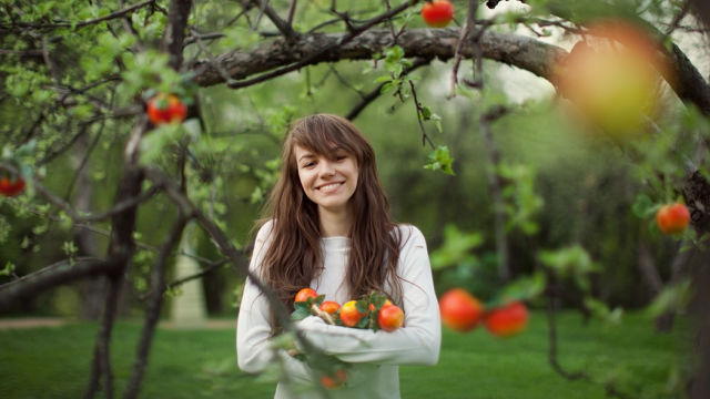 Ein Mädchen, das Früchte umarmt und lächelt.