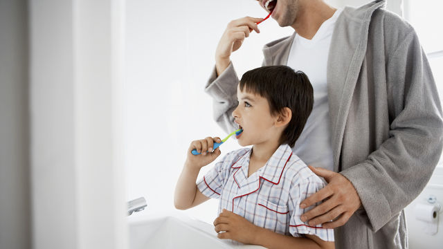 Vater und Sohn putzen sich die Zähne