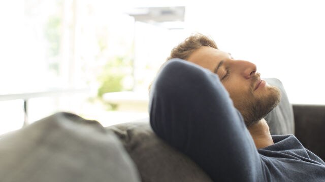 Mann, der auf dem Sofa liegt und sich ausruht.