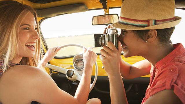Mädchen lächelnd auf einem Auto beim Fotografieren